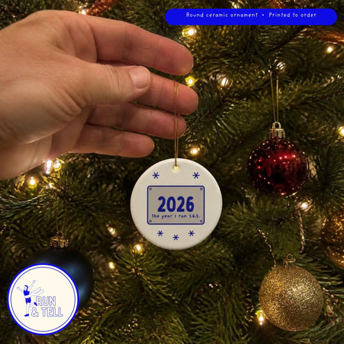 2026: The Year I Ran 26.2 ornament hanging on a Christmas tree among glass baubles